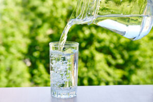 Aus einer gläsernen Karaffe wird Wasser in ein Glas gegossen.